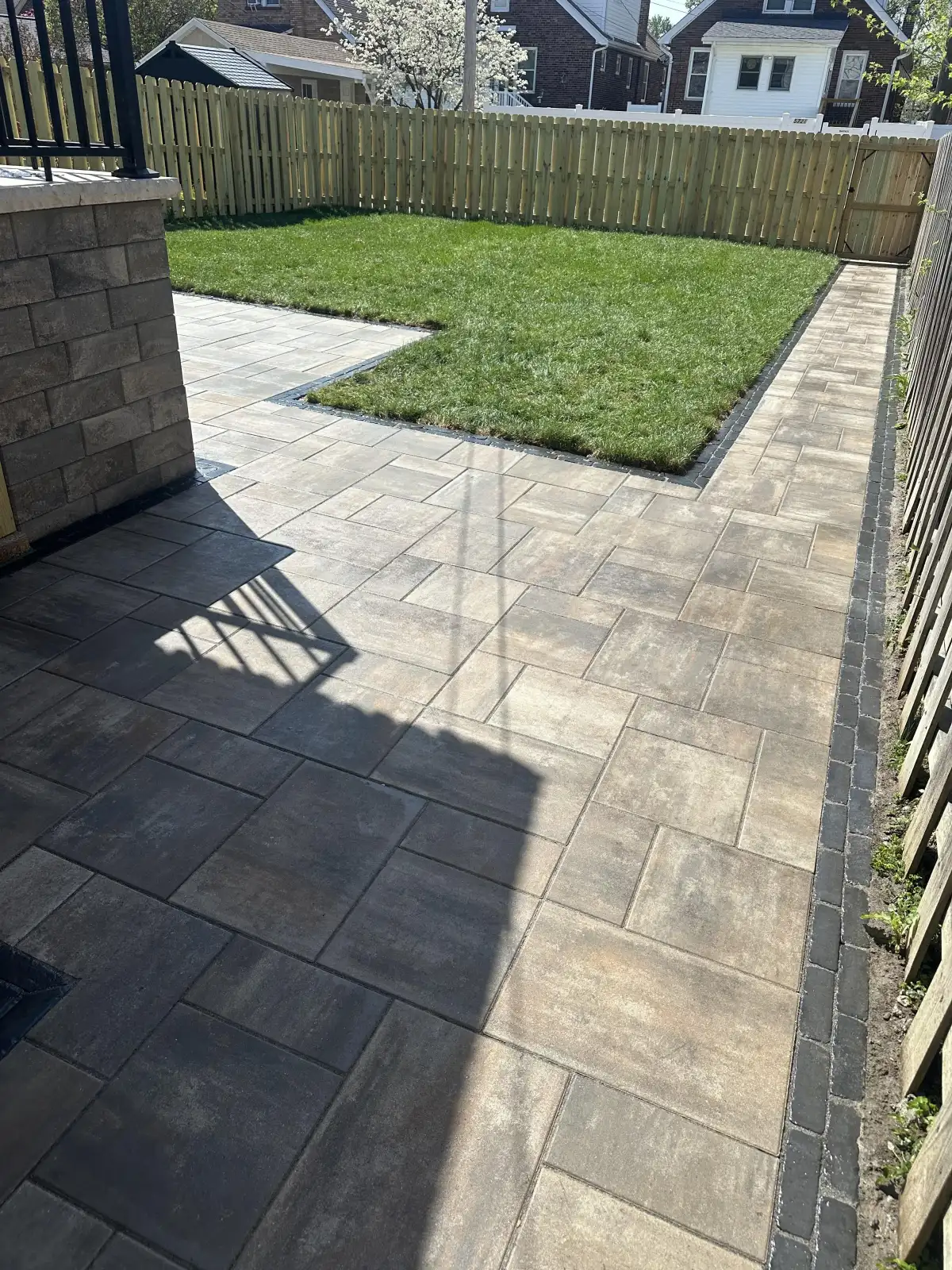 Aerial view of large paver patio with dark border by Green Operations