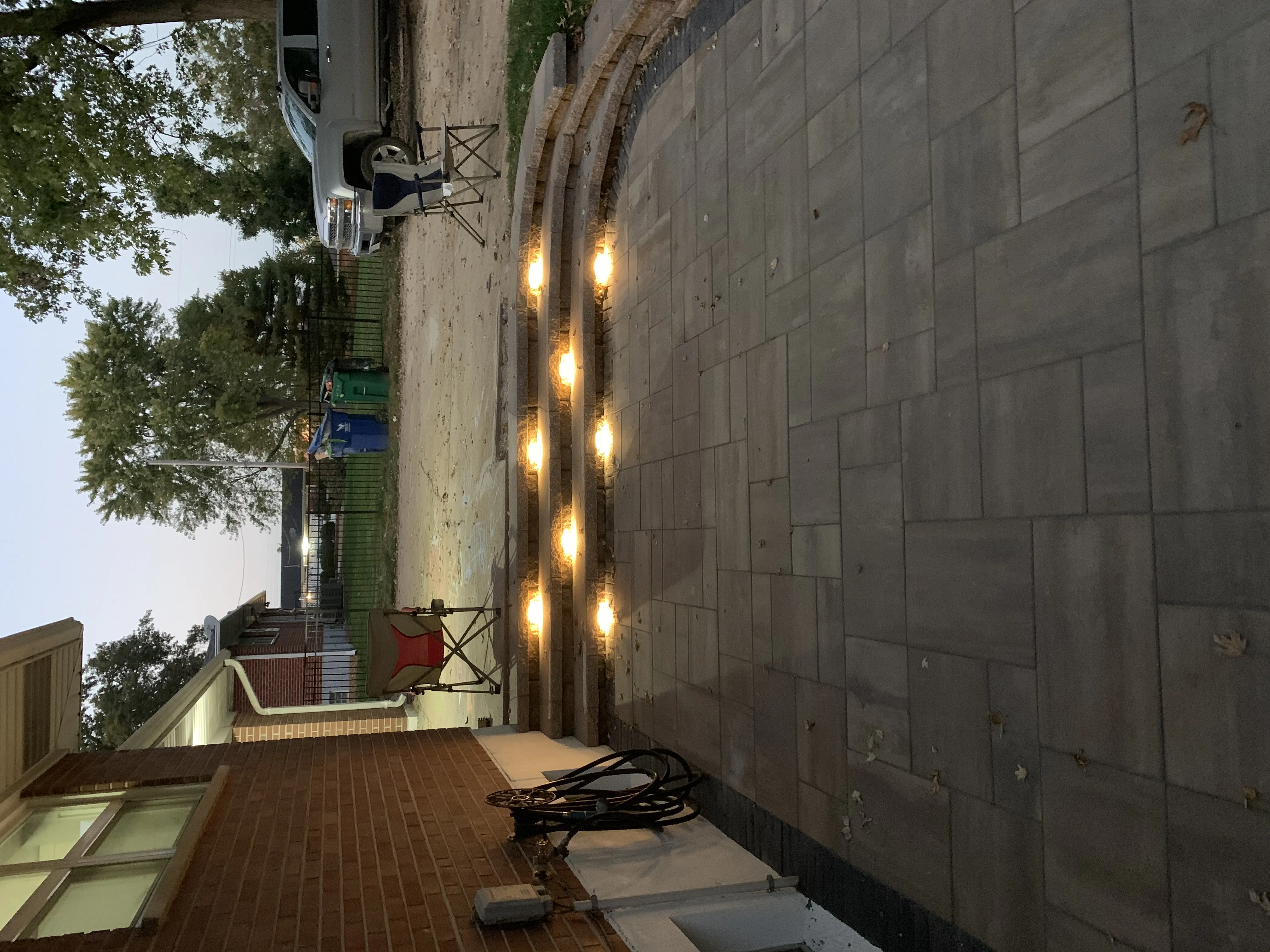 Paver patio with string lights and step lighting at dusk