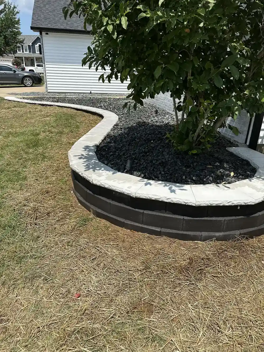 Raised stone planter with black rock mulch and landscaping