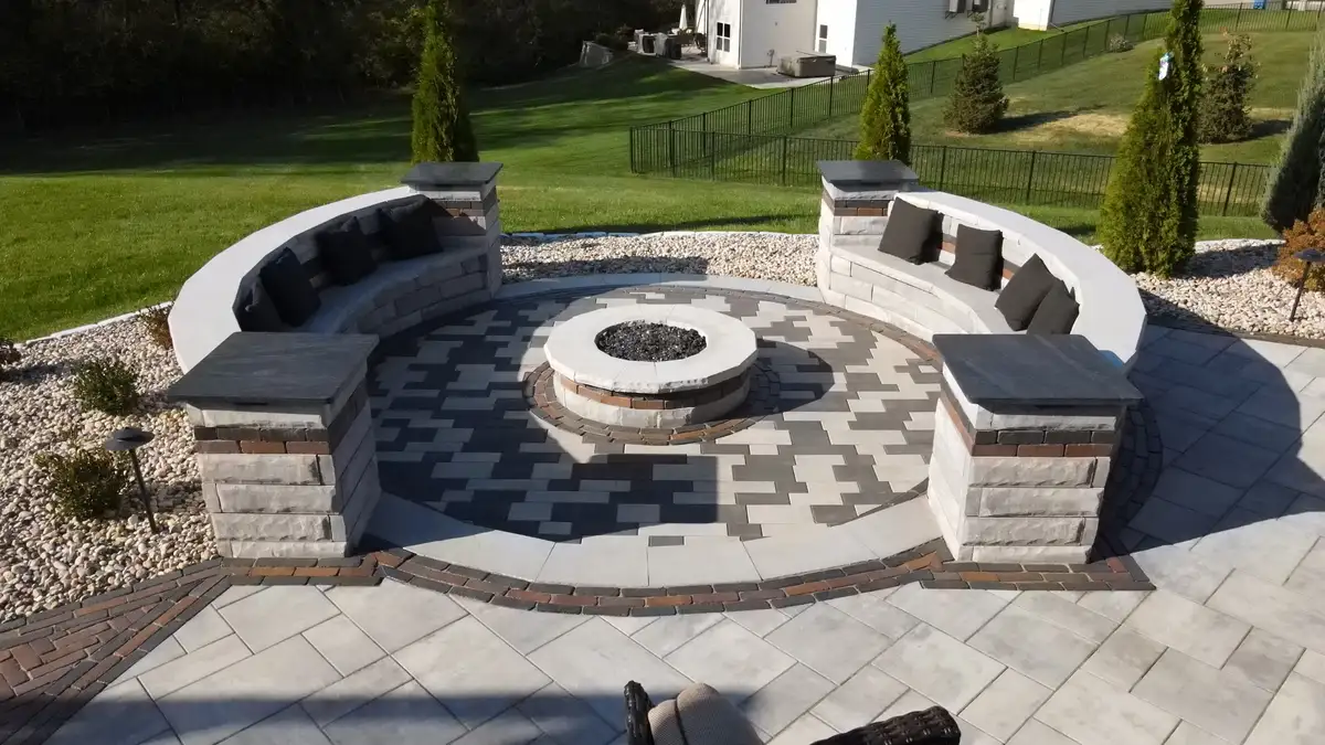 Fire pit with seating wall and stone pillars near pool area