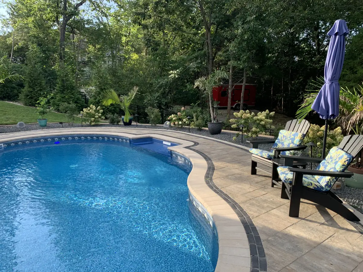 Finished pool with paver deck, Adirondack chairs, and hydrangeas in St. Louis