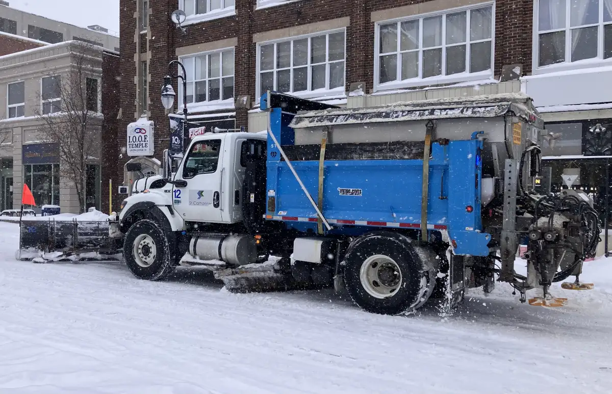 Snow plow truck clearing a snowy road during a winter storm